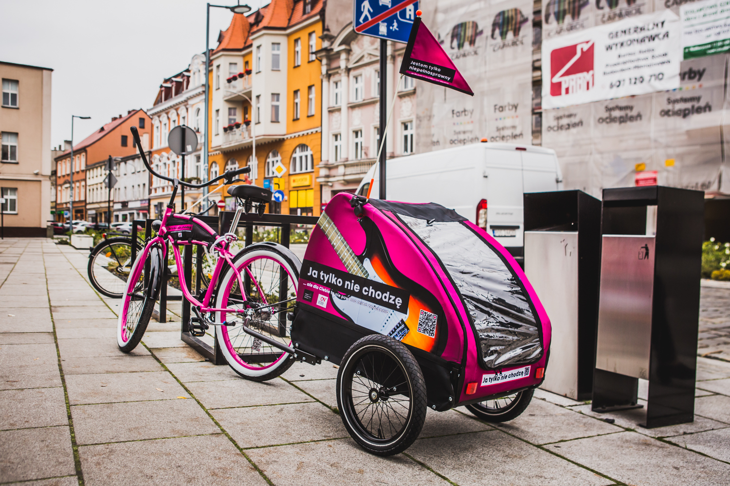 Różowy rower z przyczepką na Rynku ramach projektu “Jestem tylko niepełnosprawny” dofinansowanego z funduszy EOG i budżetu państwa
