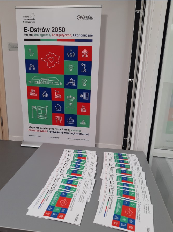 Conference opening the project "E-Ostrów 2050 – Ecological, Energy and Economic City".The photo shows leaflets about the project and a roll-up with the logo of EEA funds. 